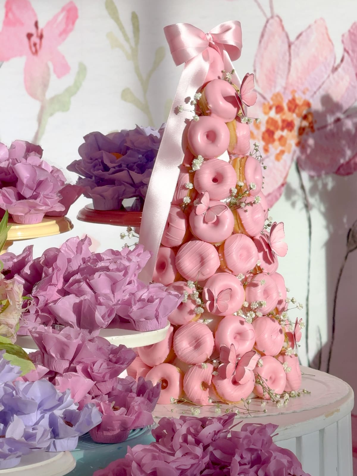 Torre de donuts cor-de-rosa decorada com flores e laço
